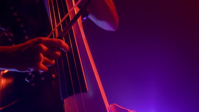Cellist with electronic cello performs on stage.