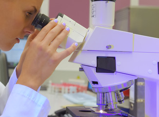 A young student takes up her duties as lab  assistant. She wears a white smock to work  with while...