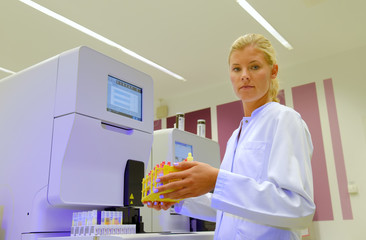 A young student takes up her duties as lab  assistant. She wears a white smock to work  with while...