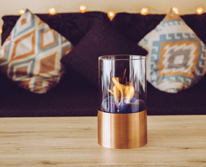 Freestanding portable glass and copper metal fireplace burning bio ethanol gas on living room...