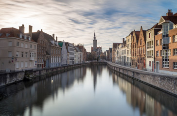 Fototapeta na wymiar Canals of Bruges in a sunny winter afternoon with the church of our lady in the background, Bruges, Belgium