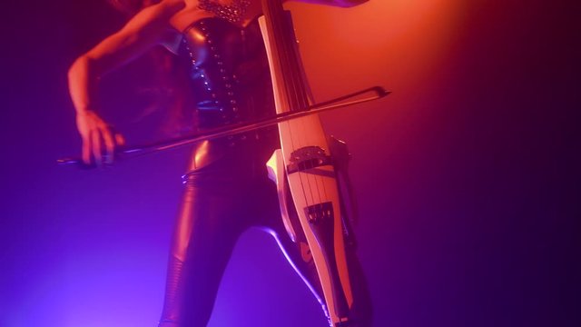 Cellist with electronic cello performs on stage.