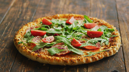 Side view of delicious italian pizza served on dark brown wooden table with copy space