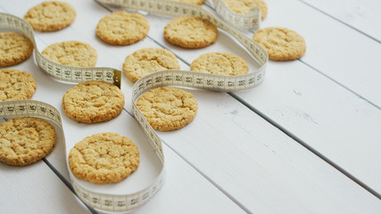 Gluten free healthy oatmeal cookies on white rustic wood bacground. Fitness concept with measure tape. Side view with copy space, flat lay.