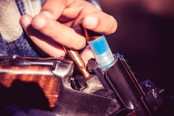 Man is charging a hunting rifle. Hunter with shotgun gun on hunt. American hunting rifles. Gun...