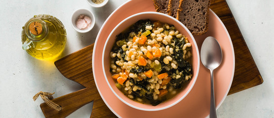 banner of winter warming soup with kale and beans on the table with whole grain bread. healthy...