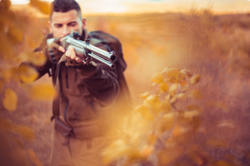 Autumn hunting season. Hunter aiming rifle in forest. Barrel of a gun.