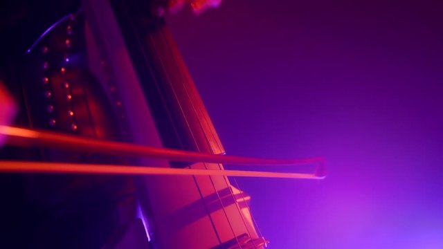 Cellist with electronic cello performs on stage.