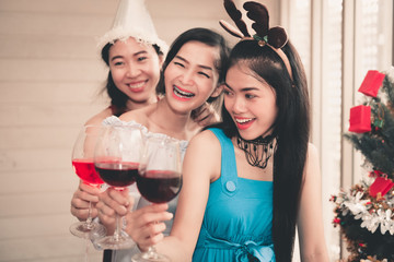 Young Women Having Fun in Celebration Christmas Party Together While Holding Red Wine Glass, Portrait of Asian Girl Teenagers are Happiness in Holiday X'Mas Party. Holiday Celebrating Event