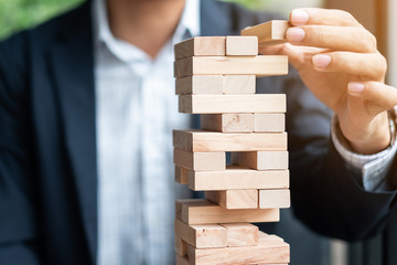 Businessman hand placing or pulling wooden block on the tower. Business planning, Risk Management, Solution and strategy Concepts