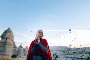 Naklejka premium girl in ethnic clothes at dawn watching the flight a lot of balloons fly over the valley of love