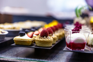 Many different small cakes are on the window of the candy shop.