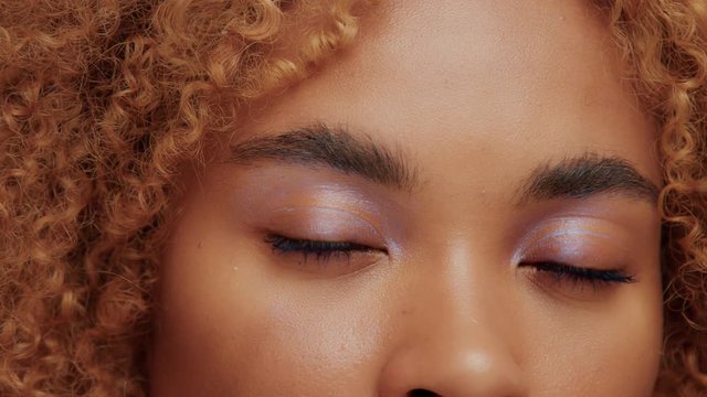 panned video of black woman brown eyes with cold blue highlighter on it watching on camera