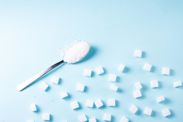Sugar cubes and spoon with crystalines on blue background