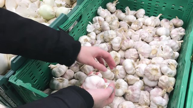 Young caucasian woman choosing garlic in the grocery department of the supermarket.