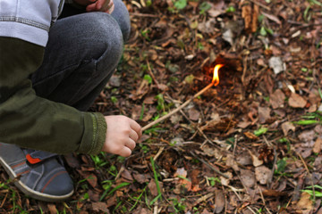 A child playing with fire in the woods.