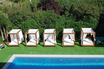 Four poster sunbeds by a swimming pool in Puerto Pollensa on the Spanish island of Majorca.