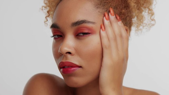 pan video portrait of black mixed race woman with bright red makeup and long gel orange nails