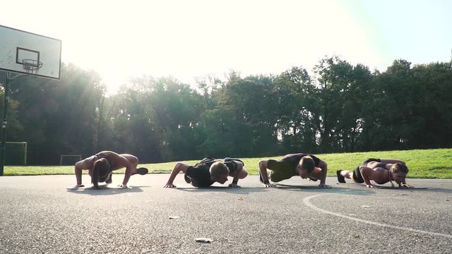 two beautiful girls and two cool boys doing alligator push ups outdoor in the morning sun