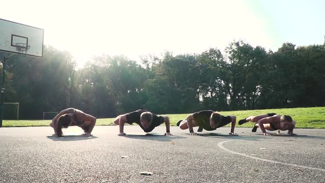two beautiful girls and two cool boys doing alligator push ups outdoor in the morning sun