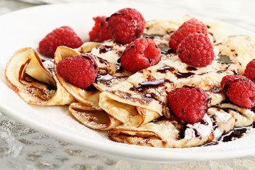 Delicious golden palacinky pancakes or Czech Pancakes with fresh raspberries and sweet chocolate syrup. Extreme shallow depth of field.