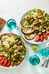 Fototapeta na wymiar an appetizing dinner or lunch from a salad with tomatoes, grilled eggplants and legume falafel with sesame tahini dressing. Vegan healthy food for the whole family