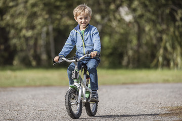 Smiling little boy on a bicycle while learning to ride