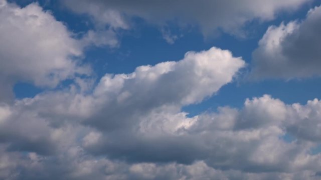 Fluffy clouds on blue sky moving fast. Beautiful cinematic background. 4K time lapse.
