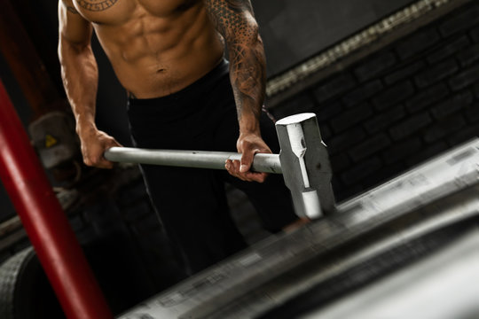 Man Is Hitting Tire With A Sledgehammer During His Cross Training Workout