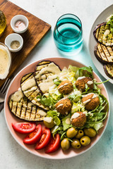 an appetizing dinner or lunch from a salad with tomatoes, grilled eggplants and legume falafel with sesame tahini dressing. Vegan healthy food for the whole family