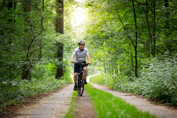 Senior man biking in forest, enjoying healthy active lifestyle outdoors in summer