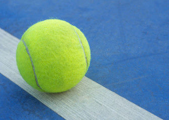 Tennis ball on line in tennis court.