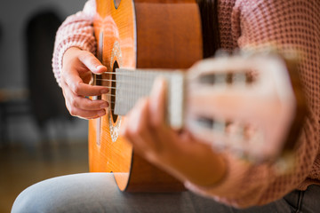 close up of woman  hand pressing chords on guitar's bar, music and art concept