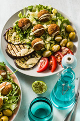 an appetizing dinner or lunch from a salad with tomatoes, grilled eggplants and legume falafel with sesame tahini dressing. Vegan healthy food for the whole family