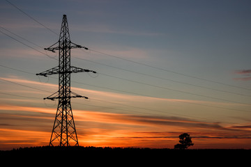 The line of support for electric gears against a sunset.