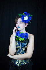 Sensual young woman touching face and looking away with blue flowers composition  