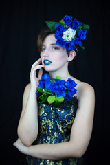 Sensual young woman touching face and looking at camera with blue flowers composition  