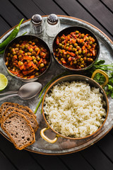 vegan curry with green peas and basmati rice served on a wooden table tray, healthy Indian comfort food