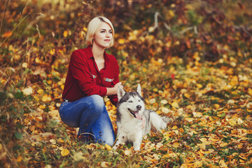 Beautiful caucasian girl plays with husky dog in autumn forest