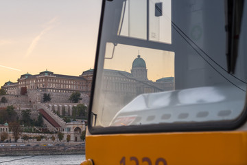 Obraz premium Unique sunset view of Buda Castle in Budapest with a yellow tram on line 2 in the foreground