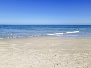 Fototapeta na wymiar Empty sand beach with blue sea and blue sky background.