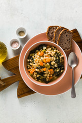 winter warming soup with kale and beans on the table with whole grain bread. healthy vegan food