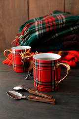 Holiday mugs with hot tea on wood table