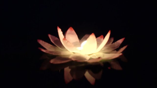 Festival of lanterns on the water. Water lantern in the shape of a Lotus with a candle flame floating at night on the water.