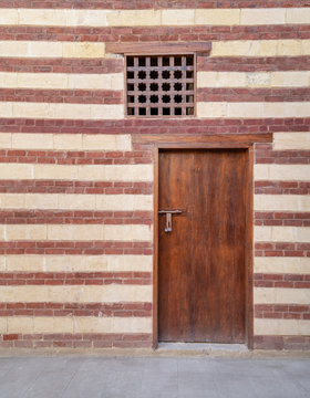 Background of old wall with red bricks and yellow stones, wooden closed door and window, Cairo, Egypt