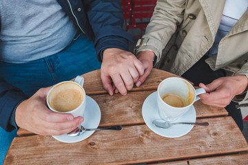 couple holding hands while drinking latte in outdoors cafe