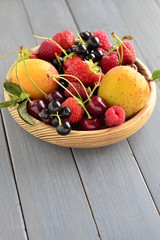 Summer berries and fruits in a wooden bowl