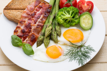 Fried eggs with bacon on the wooden table.