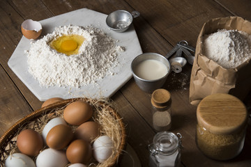 Bakery ingredients : flour, eggs, butter, sugar and rolling pin on vintage wood table, Sweet baking concept