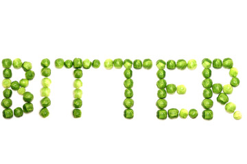 Brussel sprouts spelling the word bitter on a plain white background